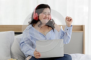Asian young happy funny fat chubby oversized woman wears big red headphones around head listening to music and sit enjoy   alone