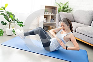 Asian young healthy woman exercising on yoga mat at home, she is doing a Russian twist