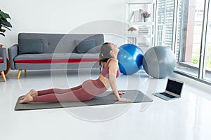 Asian young healthy woman in sportware practicing yoga at home, Sport girl meditating in living room at home