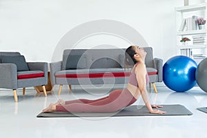 Asian young healthy woman wearing sportware online fitness training with laptop at home