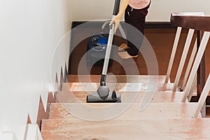 Asian young housekeeper hoovering stairwell in a house.