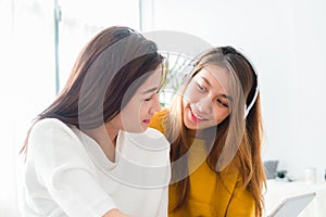 Asian young lesbian couple listening to music together in a happy moment of love in the bedroom.