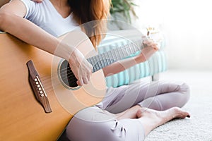 Asian young lesbian couple playing guitar for her lover with love moment in the bedroom surrounded with warm sunlight.