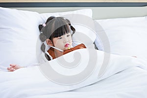 Asian young little cute preschooler daughter girl laying down preparing to sleep on cozy pillow under thick warm white blanket on