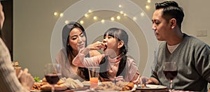 Asian young little girl enjoy eating her meal crispy fried chicken together with family in christmas and new year party. The kid f