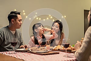 Asian young little girl enjoy eating her meal crispy fried chicken together with family in christmas and new year party. The kid f