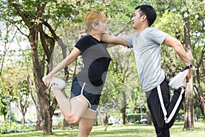 Asian young love couple workout on stretching their bodies together to be prepared for the exercise.