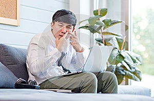 Asian young male businessman employee in formal business outfit sitting on cozy sofa couch with laptop holding hands and fingers