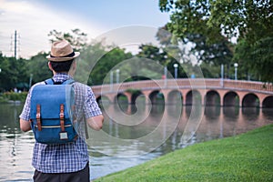 Asian young man age 25-30 year tourists backpacker are watching the beauty of the bridge and river in the park and tourist
