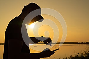 Asian young man checking time on his sports watch near sunset