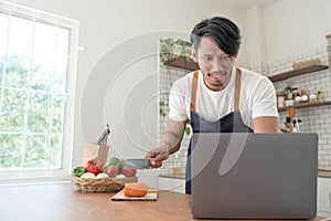 An Asian young man cooking , preparing breakfast with healthy food in kitchen at home , healthy lifestyle