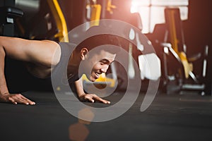 Asian young man doing push-ups at the gym. Muscular female doing