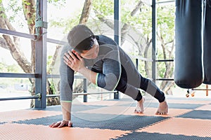 Asian young man exercise doing push-ups workout by one hand in fitness gym