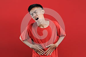 Asian young man getting stomach ache or getting abdominal pain health problem discomfort diarrhea