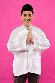 Asian young man with greeting gesture in cap with pink