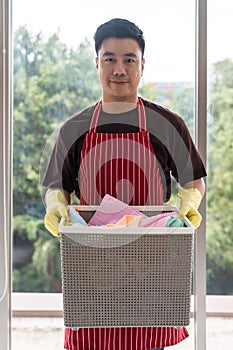 Asian young man hold basket with cloths to do laundry at home