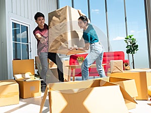 Asian young man point finger to open box direction for moving a big cardboard with pretty woman when relocation studio home