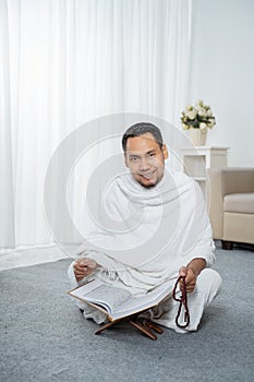 Asian young man praying with Al-Qur`an and prayer beads