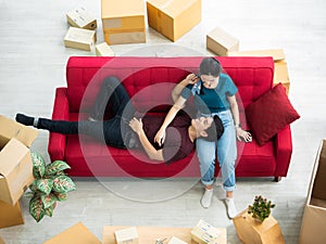 Asian young man smile and lie on her lap after packing cardboard box for send online order to loyalty customer