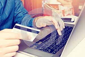 Asian young man typing laptop keyboard and holding credit card w