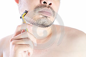 Asian young man using a razor shaving his beard. Do not use cream. on white background and clipping path. Clean face treatment