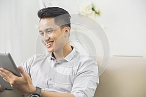 asian young man using tablet pc at home