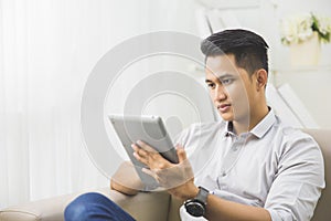 Asian young man using tablet pc at home