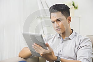 Asian young man using tablet pc at home