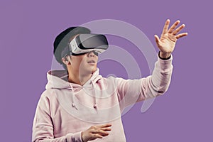 Asian young man using virtual reality headset isolated over violet background