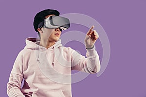 Asian young man using virtual reality headset over violet background