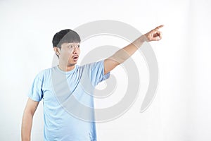 An asian young man wearing a blue t-shirt pointing at something with an amaze expression