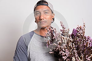 Asian young man wearing casual t-shirt and cap holding a bouquet