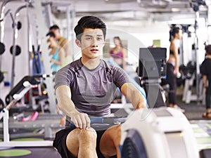 Asian young man working out on rowing machine