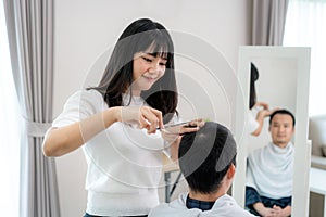 Asian young man with her girlfriend hairdresser cutting hair with Haircutting scissors at home they stay at home during time of photo