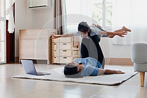 Asian young mother and her daughter doing stretching fitness exercise yoga together at home.