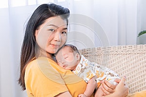 Asian young mother holding newborn baby, Beautiful mom of nursing. Adorable little boy sleeping on mother`s chest. Happy woman