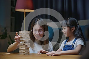 Asian young mother playing game in wood block with her little daughter in home