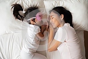 Asian young mum and little daughter sleep in cozy bed