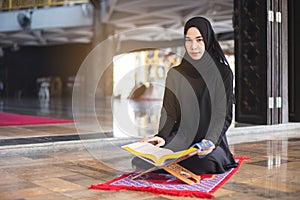 Asian young muslim woman reading Quran.