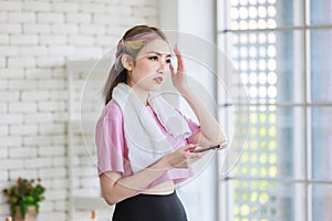 Asian young pretty cheerful happy healthy fitness girl in sexy sportswear with headphones listening to music playlist using smart