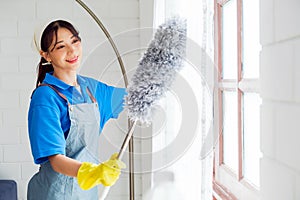 Asian young professional cleaning service woman worker working in the house. The girl cleans the curtain and window.