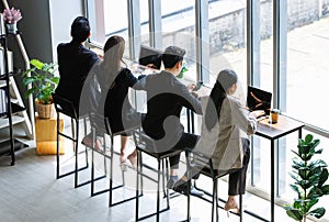 Asian young professional successful businessman and businesswoman colleagues in formal business suit sitting at cafeteria table