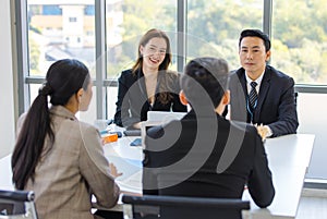 Asian young professional successful businesswoman and businessman employee in formal suit sitting at working desk negotiating