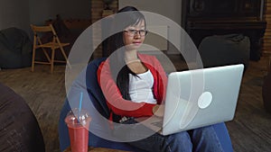 Asian young professional woman working on computer drinking a smoothies.