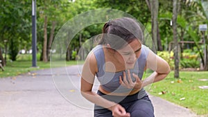 Asian young runner workout standing bent over and catching her breath and suffering from heat stroke and heart attack outdoors