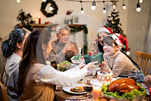 Asian young sister give greeting present box to child girl when family eating dinner food, drink and dessert sweet on the table in