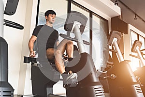 Asian young sport man riding stationary bicycle in fitness gym. Man working out on spinning bikes in gym. People lifestyles and