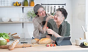 Asian young sweet couple cooking breakfast together in home kitchen. Beautiful wife smiling embracing her husband from back while