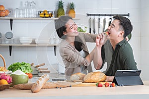 Asian young sweet couple cooking breakfast together in home kitchen. Beautiful wife smiling embracing her husband from back while