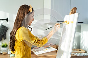 Asian young talented woman artist coloring on painting board in house. Attractive beautiful female draw art picture, creating